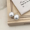 Close-up of large pearl stud earrings with metallic posts on vintage book background - 14mm Shell Pearl Stud