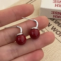 Dettaglio di orecchini di perle rosse con ganci d'argento tenuti tra le dita per scala - Perla Rossa Gancio Argentato (A-716)