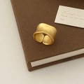 Vista detallada de anillo ancho dorado mate con diseño irregular sobre libro vintage - Oro Mate Anillo Ancho Chapado en Oro