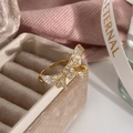 Detailansicht eines goldfarbenen Schleifenrings mit Zirkonia-Besatz auf Samtschatulle - Goldener Bowknot Ring mit Mikropflaster Zirkonia