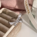 Makroaufnahme eines silbernen Schleifenrings mit Zirkonia-Kristallen auf einer Samtbox - Silberner Bowknot Ring mit Mikropflaster Zirkonia