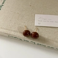 Dettaglio di orecchini a sfera marrone scuro con finitura lucida su un libro d'epoca - 12mm Cioccolato