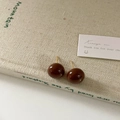 Primo piano dettagliato di orecchini a sfera in smalto marrone su sfondo di libro beige - 14mm Cioccolato