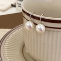 Detalle de pendientes de perlas francesas colgados en una taza de cerámica vintage - Pendientes de Perlas Mabe Plateados