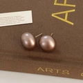Detail von matten Bronze-Halbkreis-Ohrsteckern vor einem ästhetischen Vintage-Hintergrund - Dunkelbraun