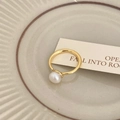 Detailansicht einer weißen Perle auf einem minimalistischen Goldring auf einer Keramikschale - Offener Einzelperlenstil / Gold