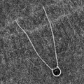 Detalle macro de colgante de piedra natural con soporte en U sobre tela texturizada - Collar de Plata Con Perla Negra