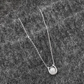 Primer plano de collar con colgante de herradura y piedra blanca en cadena plateada - Collar de Plata Con Perla Blanca