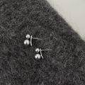 Detalle de pendientes de doble perla gris oscuro sobre fondo de punto grisáceo - Estilo Plateado / Gris