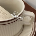 Detail of silver crisscross pearl ring with micro-inlaid zircons on a cream coffee cup - Multi-pearl Micro-pave Zircon Silver Style