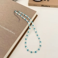 Détail du collier de perles bleues et blanches style bambou sur un livre rétro - Collier de Perles en Bambou Coquille Turquoise Bleue (B-146)