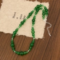 Detail van groene kralenketting met zilveren kralen en kreeftensluiting op getextureerd papier - Groene Chalcedoon Kralenketting