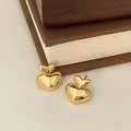 Detail showing stacked golden 3D heart stud earrings on a minimalist cream background - Gold