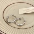 Detalle de pendientes geométricos en forma de C plateados con textura efecto líquido - Plateado