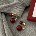 Detail of dual-bead earrings with burgundy pearls and gold metal on knit fabric - Burgundy