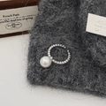 Detailed shot of an open pearl ring with zircons on a textured knitted background - White Pearl Ring With Micro-set Zircon Stones