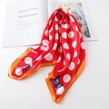 Red silk square scarf with white polka dots and blue butterfly prints on white table - Red