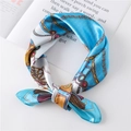 Detail of luxury silk scarf with chain pattern and carriage design on magazine - Blue