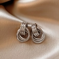 Close-up of interlocking silver layered hoop earrings on champagne silk fabric - Silver Multi-Layer Circle Stud Earrings