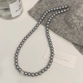 Détail d'un collier de perles grises avec pendentif zircon sur un pull en maille - Collier Perle Grise Zircon Rond