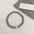 Détail d'un bracelet en perles gris foncé avec un zircon blanc étincelant au centre - Bracelet Perle Grise Zircon Rond