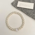 Vue détaillée d'un élégant bracelet de perles avec un zircon central sur un tissu doux - Bracelet Perle Blanche Zircon Rond