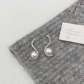 Macro shot of S-shaped silver pearl earrings with micro-pave zircons on knit background - Silver S-Shape Micro-Inlaid Style / Silver