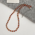 Dettaglio della collana fatta a mano con perle arancioni e blu su tessuto a maglia - Collana di Turchese Rosso E Blu Intervallata