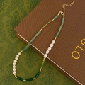 Détail d'un collier de perles d'eau douce et gemmes vertes avec fermoir doré sur livre - Collier Fait Main en Perles d'Eau Douce et Pierre Naturelle