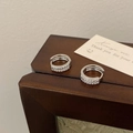 Dettaglio di orecchini a cerchio in argento con doppia fila di zirconi su legno - Orecchino a Cerchio Zircone Micro-Pave Argento