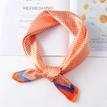 Detail of orange houndstooth silk scarf with royal blue edges on a floral magazine background - Orange