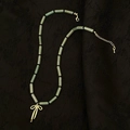 Détail du collier de perles en pierre verte avec pendentif noeud doré sur tissu noir - Collier Pendentif Nœud Style Bambou Vert Clair