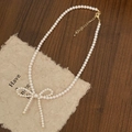 Elegant pearl necklace detail with a bow pendant and gold clasp on a vintage wood surface - 4mm Pearl Bow Knot Necklace