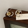 Vue macro de boucles d'oreilles créoles bicolores argent et or au style français - Créoles bicolores