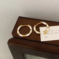 Dettaglio macro di orecchini vintage con strisce di smalto oro e bianco su legno - Orecchini a Cerchio in Smalto Bianco