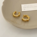 Nahaufnahme goldener strukturierter Creolen mit dreireihigem Zirkonia-Besatz auf Tablett - Spiralstruktur mit Zirkonia / Gold