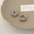 Makro-Detail von silbernen Creolen mit strukturierter Oberfläche und Zirkonia - Spiralstruktur mit Zirkonia / Silber