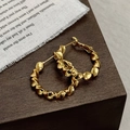 Detalle de pendientes de aro dorados con diseño en espiral de estilo vintage - Dorado