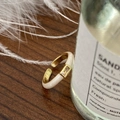 Makro-Detail des goldenen Emaille-Rings mit Zirkonia auf elegantem dunklem Holzgrund - Weiß