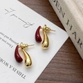 Dettaglio di orecchini a goccia in metallo dorato e smalto rosso scuro su libro - Rosso Ancora (Base Oro)