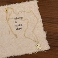 Collana con ciondolo a forma di papera dorata e zirconi su sfondo di carta beige - Collana con anatroccolo giallo dagli occhi neri