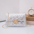 Close-up of sparkling silver sequins and golden chain strap on a chic evening crossbody bag - White