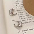 Dettaglio di orecchini a spirale in argento lucido su carta vintage - Argento