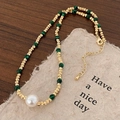 Dettaglio della collana con perle dorate sfaccettate, malachite verde e grande perla bianca - Stile Turchese Dorato (Texture di Malachite Verde)