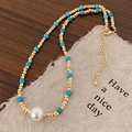 Dettaglio della collana con perle dorate, pietre turchesi e una grande perla bianca centrale - Stile Turchese Blu Dorato (Texture Celeste)