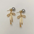 Gros plan de boucles d'oreilles nœud doré avec perles grises et métal poli brillant - Boucles d'Oreilles Nœud Doré Brillant Perle Grise