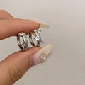 Detailaufnahme kleiner silberner Creolen mit funkelnden Zirkonia auf neutralem Hintergrund - Silber