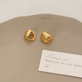 Dettaglio degli orecchini a cerchio quadrati dorati lucidi su un piatto di ceramica - Oro