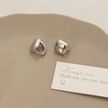 Dettaglio macro di orecchini a cerchio quadrati color argento su piatto ceramica - Argento