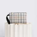 Close-up of checkered clutch bag with black leather wrist strap and golden zipper - Apricot (Beige and Black Grid)